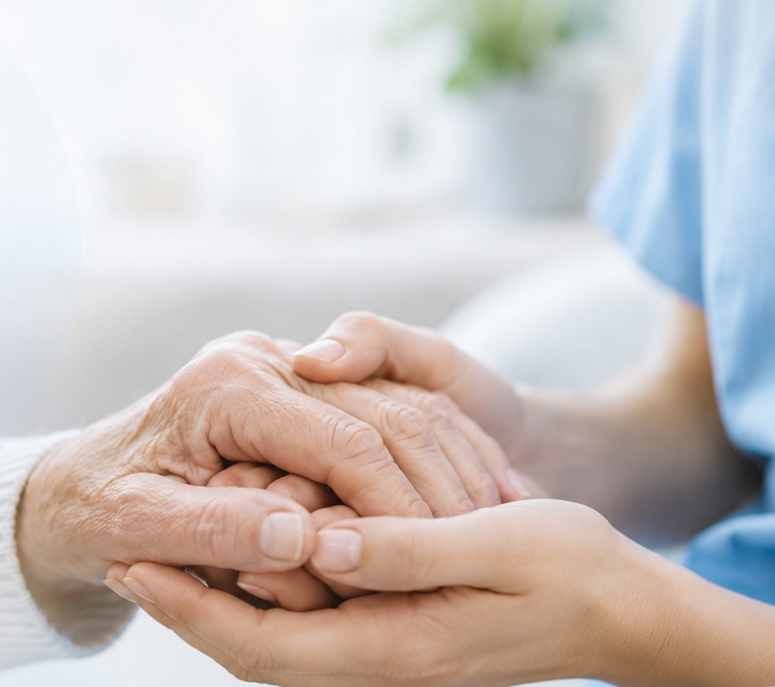 Ręce opiekunki i seniorki złączone w geście wsparcia